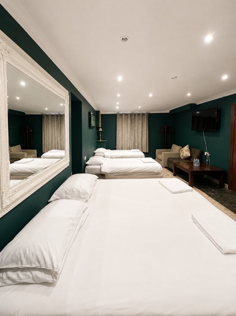 Family room with multiple beds, seating area and wall-mounted TV